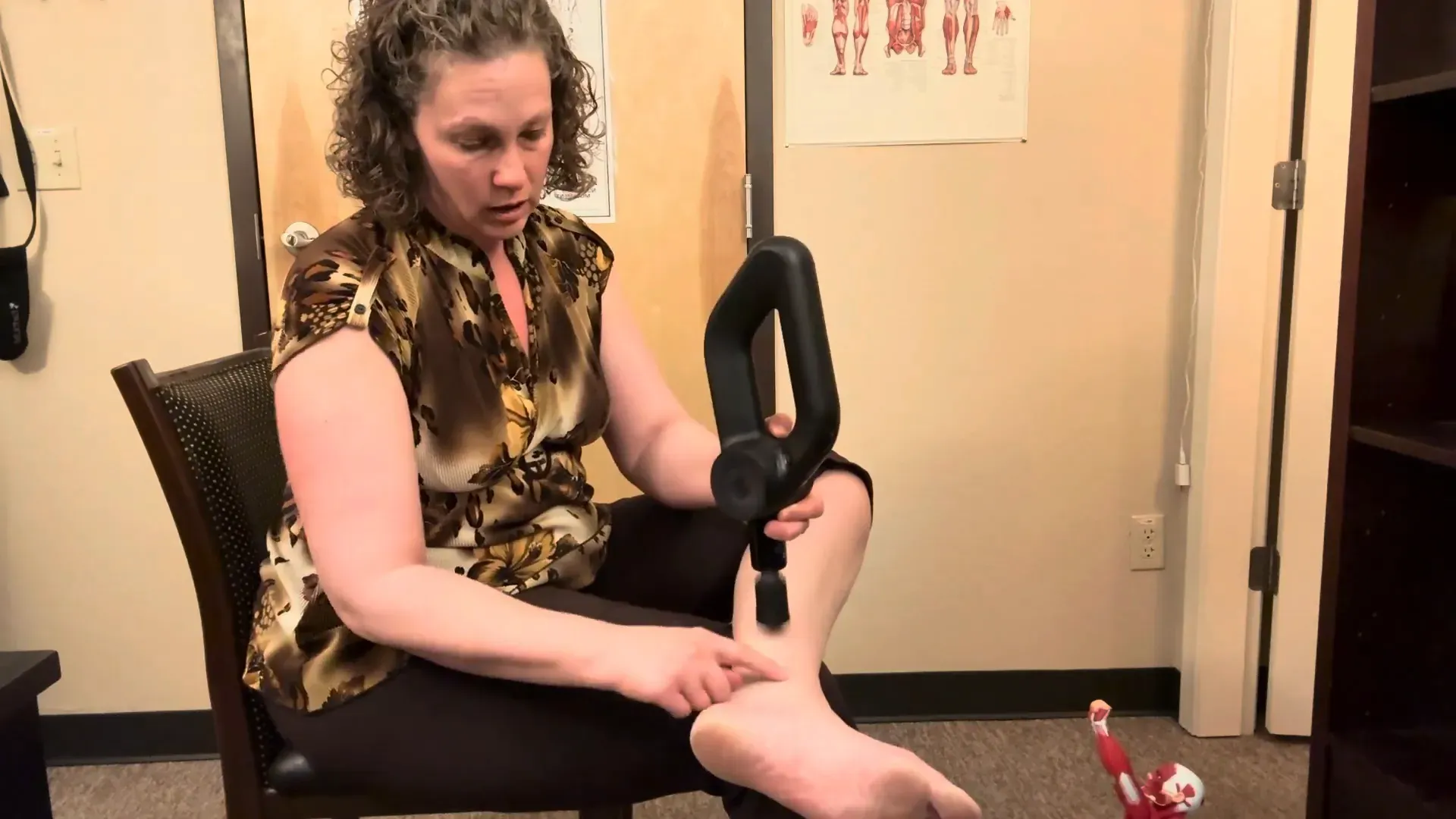Massage gun moving down side of calf muscle near ankle