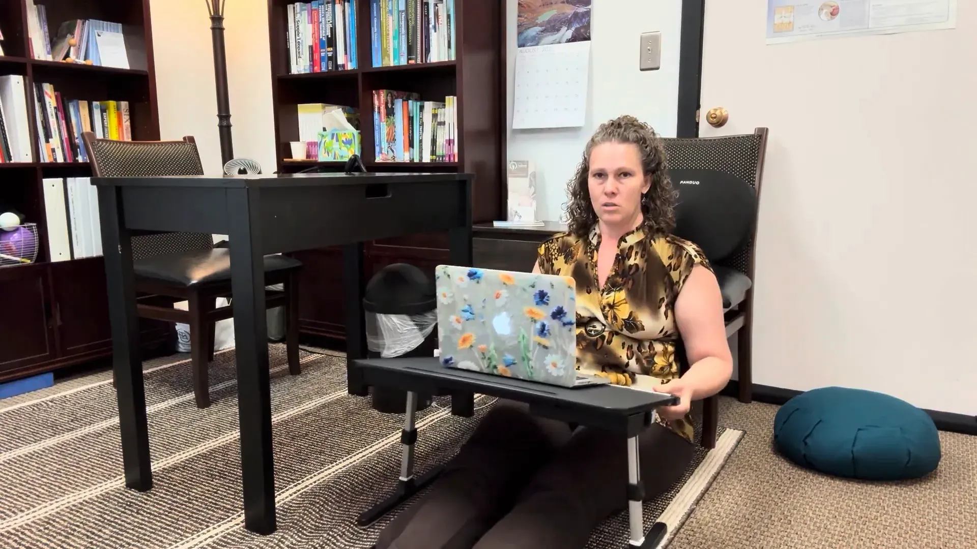 Sitting against a wall with legs out and floor desk in front