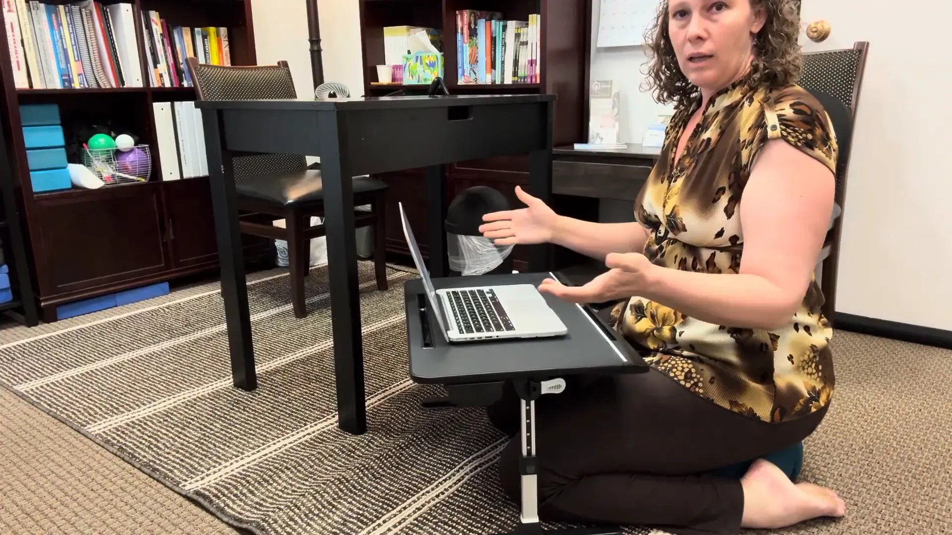 Emmy showing the portable floor desk with laptop